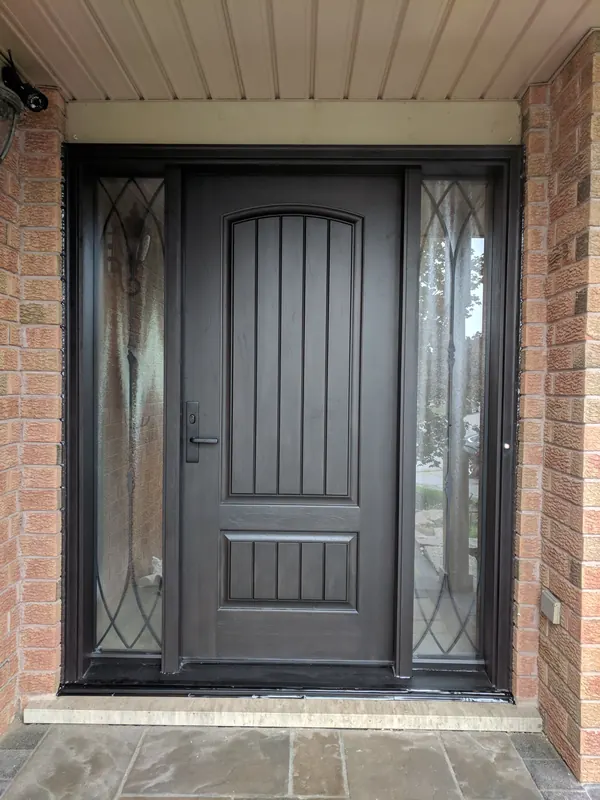Dark fiberglass entry door with wrought-iron glass sidelites on a brick porch