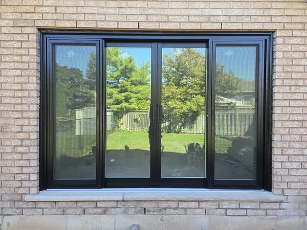 Black-frame sliding patio door in a tan brick wall