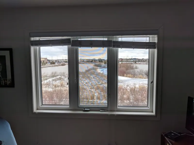 After: the same three-panel window with clear new glass and a sharp view of the pond