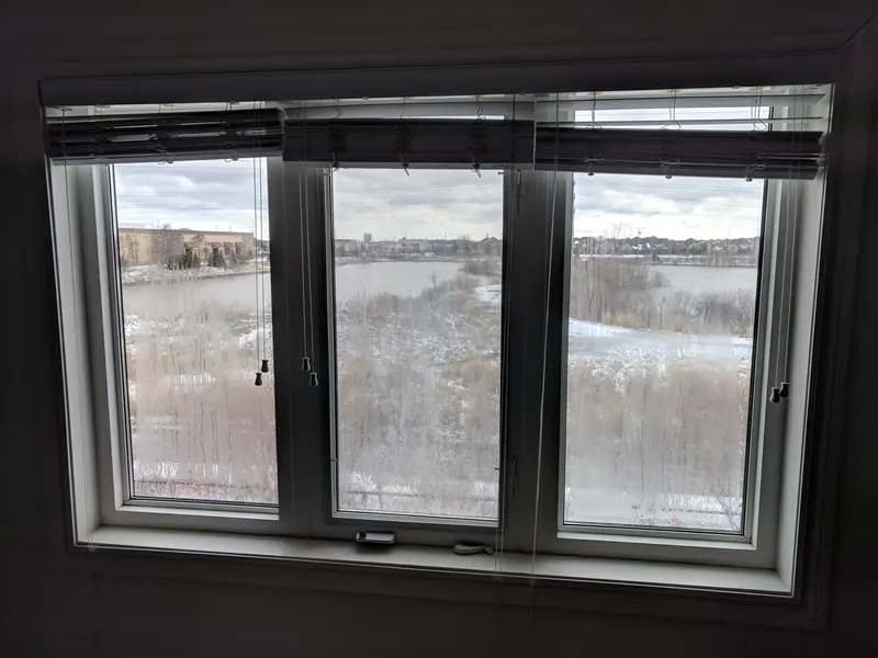 Before: three-panel window with cloudy glass from a failed seal, blurring the view of a pond