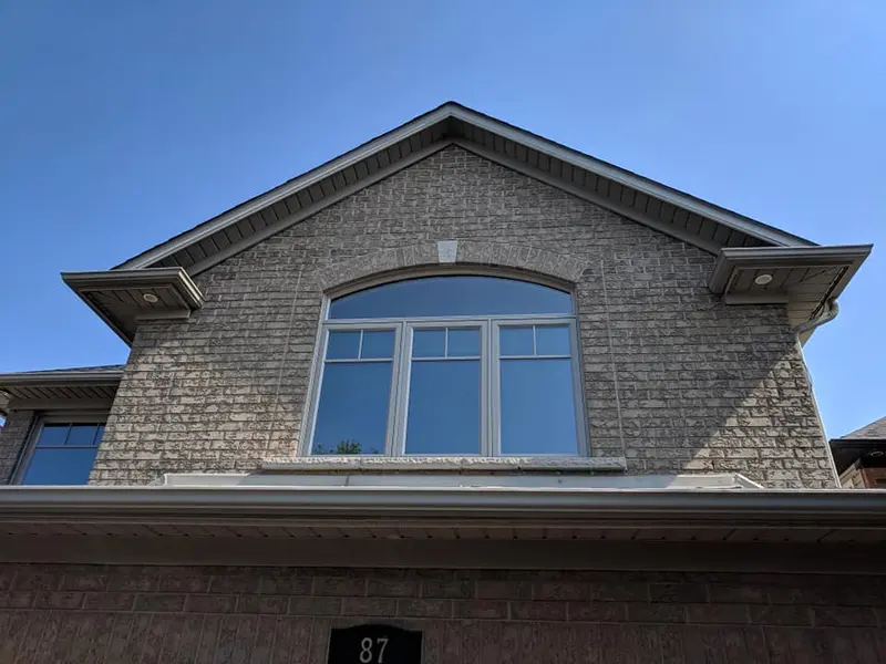New vinyl replacement window with an arched top in a brick gable