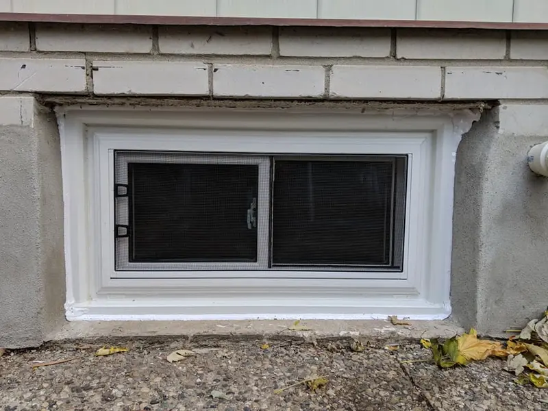 New vinyl basement window installed in a concrete foundation