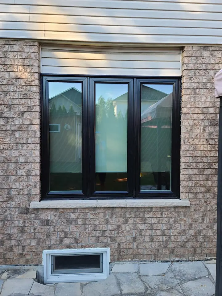 New black-frame vinyl casement window in a brick wall