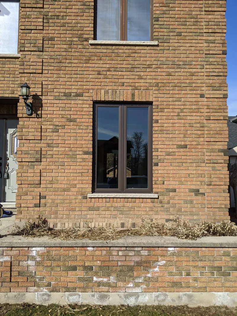 New black-frame vinyl replacement window in a brick wall