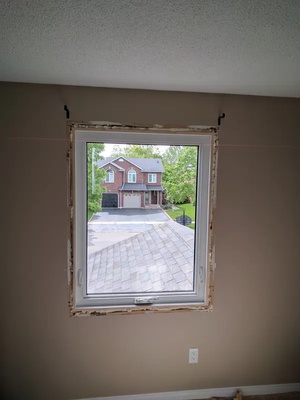New vinyl window set into the opening, with insulating foam around the frame and the trim still off